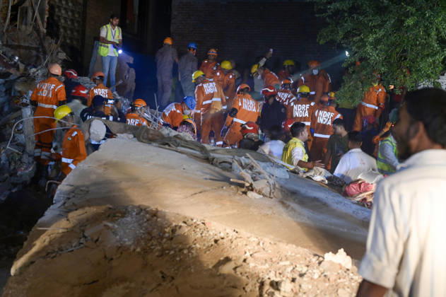 NEW DELHI, INDIA - OCTOBER 7: National Disaster Response Force (NDRF) jawans, Delhi Fire Service personnel, and local residents navigate heavy rubble during a search and rescue operation after a four-storey residential building collapsed in the New Seemapuri area of Shahdara on October 7, 2026, in New Delhi, India. The structural collapse occurred around 3:30 PM behind the local fish market, trapping multiple residents under concrete slabs and damaging two adjoining houses. At least one minor died while eight people were rescued and rushed to Rajiv Gandhi Super Speciality Hospital for emergency medical treatment as sniffer dogs and excavators worked late into the evening to locate remaining trapped survivors. (Photo by Raj K Raj Hindustan T