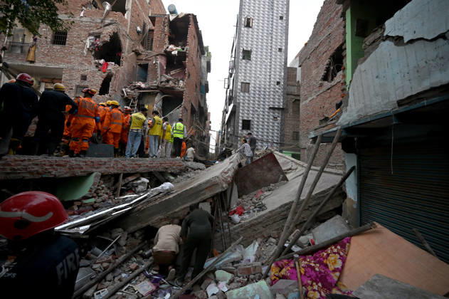 NEW DELHI, INDIA - OCTOBER 7: National Disaster Response Force (NDRF) jawans, Delhi Fire Service personnel, and local residents navigate heavy rubble during a search and rescue operation after a four-storey residential building collapsed in the New Seemapuri area of Shahdara on October 7, 2026, in New Delhi, India. The structural collapse occurred around 3:30 PM behind the local fish market, trapping multiple residents under concrete slabs and damaging two adjoining houses. At least one minor died while eight people were rescued and rushed to Rajiv Gandhi Super Speciality Hospital for emergency medical treatment as sniffer dogs and excavators worked late into the evening to locate remaining trapped survivors. (Photo by Ishant Chauhan Hindus