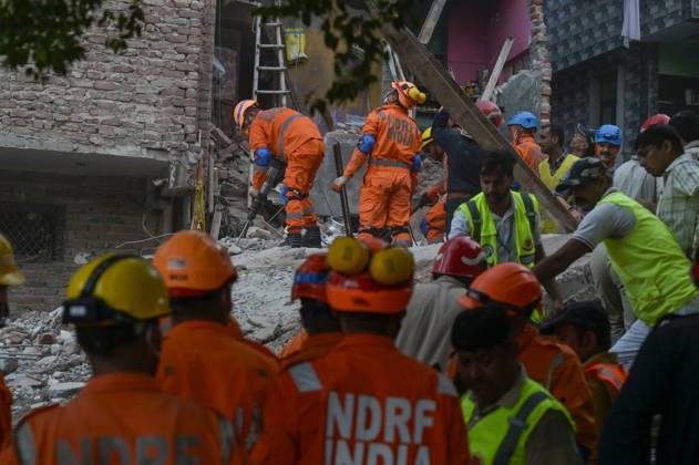 NEW DELHI, INDIA - OCTOBER 7: National Disaster Response Force (NDRF) jawans, Delhi Fire Service personnel, and local residents navigate heavy rubble during a search and rescue operation after a four-storey residential building collapsed in the New Seemapuri area of Shahdara on October 7, 2026, in New Delhi, India. The structural collapse occurred around 3:30 PM behind the local fish market, trapping multiple residents under concrete slabs and damaging two adjoining houses. At least one minor died while eight people were rescued and rushed to Rajiv Gandhi Super Speciality Hospital for emergency medical treatment as sniffer dogs and excavators worked late into the evening to locate remaining trapped survivors. (Photo by Raj K Raj Hindustan T