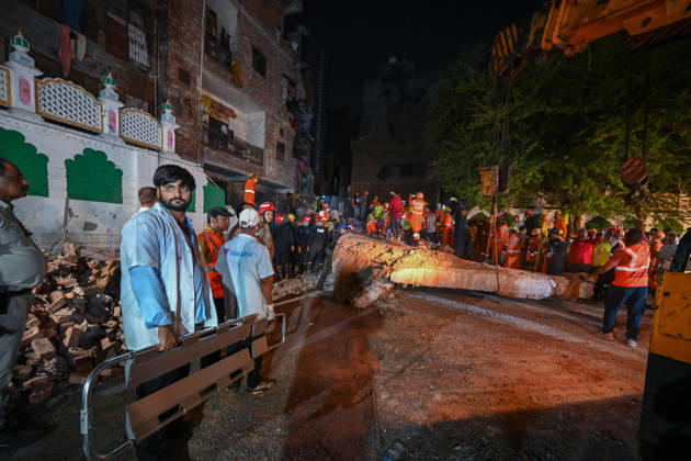 NEW DELHI, INDIA - OCTOBER 7: National Disaster Response Force (NDRF) jawans, Delhi Fire Service personnel, and local residents navigate heavy rubble during a search and rescue operation after a four-storey residential building collapsed in the New Seemapuri area of Shahdara on October 7, 2026, in New Delhi, India. The structural collapse occurred around 3:30 PM behind the local fish market, trapping multiple residents under concrete slabs and damaging two adjoining houses. At least one minor died while eight people were rescued and rushed to Rajiv Gandhi Super Speciality Hospital for emergency medical treatment as sniffer dogs and excavators worked late into the evening to locate remaining trapped survivors. (Photo by Raj K Raj Hindustan T