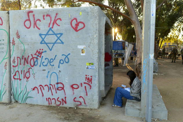 Reim Nova Memorial Marks Anniversary A woman sits beside a concrete wall marked with a Star of David and Hebrew graffiti near the memorial site at the Nova music festival memorial site near Reim, southern Israel, on October 7, 2026. The Hamas-led attack on Israel on October 7, 2023, killed about 1,200 people and saw 251 taken hostage; more than 350 people were killed at the Nova festival. Memorial events marking the third anniversary were held at the site throughout the day. Reim Southern District Israel Copyright: xTomerxNeubergx
