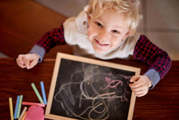 Chalk, drawing and portrait of boy at table in home for development, education or growth. Above, creative and hobby with child in apartment for hand eye coordination, imagination and motor skills. model released property released Copyright: xx