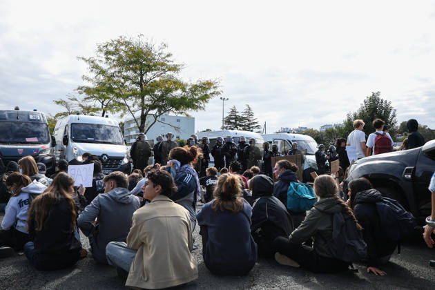 October 8, 2026, Bayonne, Nouvelle Aquitaine, France: High school students sit on the ground facing a line of riot police officers standing in front of police vans, one of them holding a sign reading ACAB , during a student protest against overcrowded classrooms, teacher shortages and school underfunding in Bayonne, southwestern France. Bayonne France - ZUMAb298 20261008_zsp_b298_008 Copyright: xJulesxBuonx
