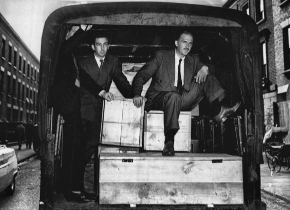 The Shop With The Deadly Secret -- Outside the shop a detective sits in a police van - on an ammunition box packed with guns. August 17, 1955. (Photo by Daily Mirror).  Copyright: xMirrorpicx 5513-85305969