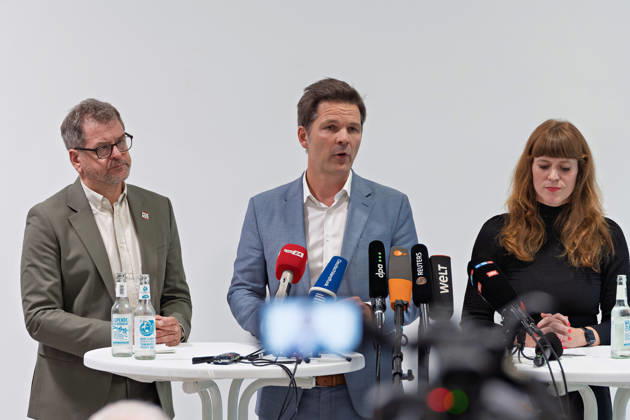 Berlin, 08.10.2026: Steffen Krach (SPD, M.) spricht neben Werner Graf (Bündnis 90 Die Grünen, l.) und Kerstin Wolter-Ehling (Die Linke, r.) beim gemeinsamen Pressestatement nach Abschluss der Vorgespräche ihrer Parteien im Foyer des Hauses der Statistik in die Mikrofone der Medien. Pressestatement von Linke, Grünen und SPD in Berlin