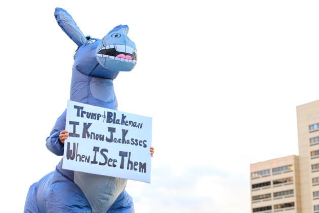 October 9, 2026, Syracuse, Ny, USA: A protestor holds up a sign dressed as a jackass during the protest against the Trump rally held at the Oncenter. Syracuse USA  - ZUMAh195 20261009_znp_h195_001 Copyright: xAlexxHamerx