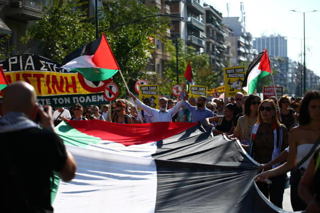 October 10, 2026, Athens, Attica, GREECE: Demonstrators carry a large Palestinian flag during a pro-Palestinian march, with a protester raising both arms in the background. Athens GREECE  - ZUMAx103 20261010_zip_x103_021 Copyright: xHarrisxXanthopoulosx