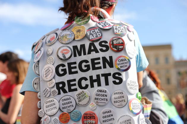 Eine Demonstrantin steht mit vielen Omas gegen Rechts Ansteckern auf dem Alten Markt während einer Demonstration für die Überprüfung rechtsextremer Parteien durch das Bundesverfassungsgericht, Potsdam, 10. Oktober 2026. Prüf-Demo in Potsdam