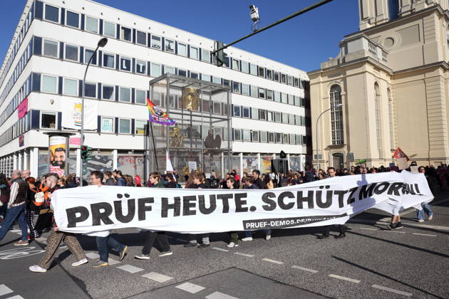 Demonstranten laufen mit Banner Prüf heute. Schütz morgen! am Rechenzentrum während einer Demonstration für die Überprüfung rechtsextremer Parteien durch das Bundesverfassungsgericht, Potsdam, 10. Oktober 2026. Prüf-Demo in Potsdam
