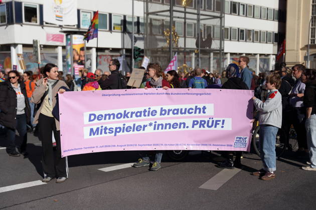 Demonstranten laufen mit Banner Demokratie braucht Mitspieler*innen. Prüf! während einer Demonstration für die Überprüfung rechtsextremer Parteien durch das Bundesverfassungsgericht, Potsdam, 10. Oktober 2026. Prüf-Demo in Potsdam