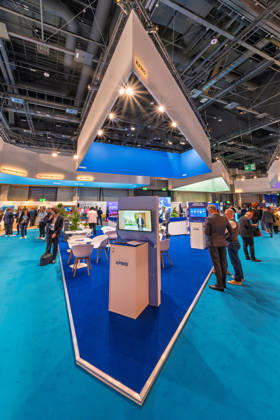 Berlin, 13.10.2026: Der Messestand von KPMG mit seinem spitz zulaufenden, beleuchteten Deckenaufbau auf der Smart Country Convention in der Halle hub27. Beratungsunternehmen wie KPMG begleiten Bund, Länder und Kommunen bei der Digitalisierung ihrer Verwaltungsprozesse. Die Smart Country Convention (SCCON) ist die Kongressmesse für die Digitalisierung des öffentlichen Sektors und wird vom Digitalverband Bitkom gemeinsam mit der Messe Berlin veranstaltet. Vom 13. bis 15. Oktober 2026 treffen sich in der Halle hub27 Vertreter aus Bund, Ländern und Kommunen mit Unternehmen der Digitalwirtschaft, um über digitale Verwaltung, Smart City und digitale Souveränität zu diskutieren. KPMG-Stand auf der Smart Country Convention