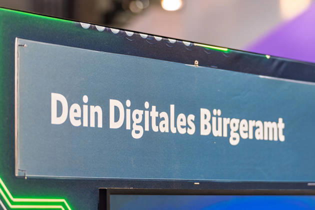 Berlin, 13.10.2026: Ein Schild mit der Aufschrift Dein Digitales Bürgeramt an einem Messestand auf der Smart Country Convention. Bund, Länder und Kommunen arbeiten daran, Verwaltungsleistungen wie Meldeangelegenheiten oder Anträge online anzubieten, damit Bürger seltener persönlich ins Amt müssen. Die Smart Country Convention (SCCON) ist die Kongressmesse für die Digitalisierung des öffentlichen Sektors und wird vom Digitalverband Bitkom gemeinsam mit der Messe Berlin veranstaltet. Vom 13. bis 15. Oktober 2026 treffen sich auf dem Berliner Messegelände Vertreter aus Bund, Ländern und Kommunen mit Unternehmen der Digitalwirtschaft, um über digitale Verwaltung, Smart City und digitale Souveränität zu diskutieren. Dein Di