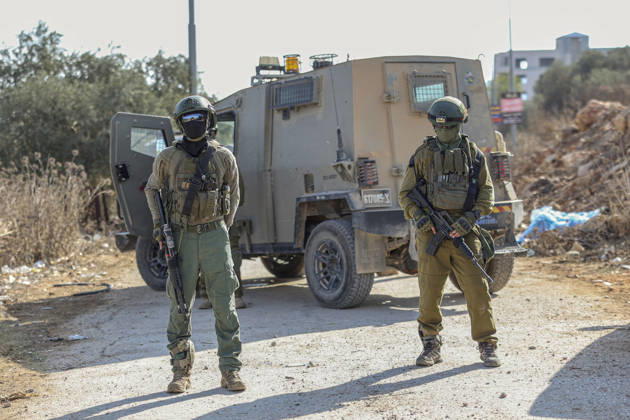 Settlers Disrupt Turmus Ayya Harvest Two armed Israeli soldiers stand in front of a tan armored vehicle parked on a dirt road in Turmus Ayya, near Ramallah, in the Israeli-occupied West Bank, on October 13, 2026. Palestinian news agency WAFA, citing local sources, reported that Israeli settlers attacked the town and tried to prevent residents from reaching their land to harvest olives. Ramallah West Bank Palestinian Territories Copyright: xMohammadxNazalx