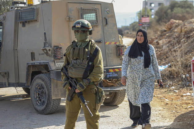 Settlers Disrupt Turmus Ayya Harvest An armed Israeli soldier stands beside a tan armored vehicle as a woman wearing a black headscarf walks nearby in Turmus Ayya, near Ramallah, in the Israeli-occupied West Bank, on October 13, 2026. Palestinian news agency WAFA, citing local sources, reported that Israeli settlers attacked the town and tried to prevent residents from reaching their land to harvest olives. Ramallah West Bank Palestinian Territories Copyright: xMohammadxNazalx