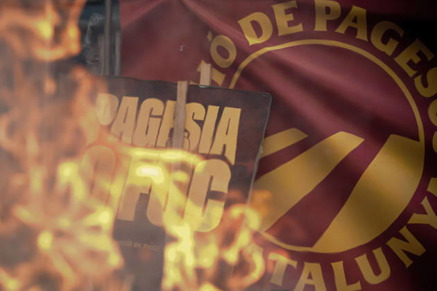 October 14, 2026, Barcelona, Catalonia, Spain: A sign reading Pagesia o foc ( Farming or Fire ) is seen through flames outside the Catalan Agriculture Ministry during a farmers protest in Barcelona demanding fair prices, lower fuel costs and protection against unfair competition from imports. Barcelona Spain  - ZUMAo105 20261014_fap_o105_003 Copyright: xMatthiasxOesterlex