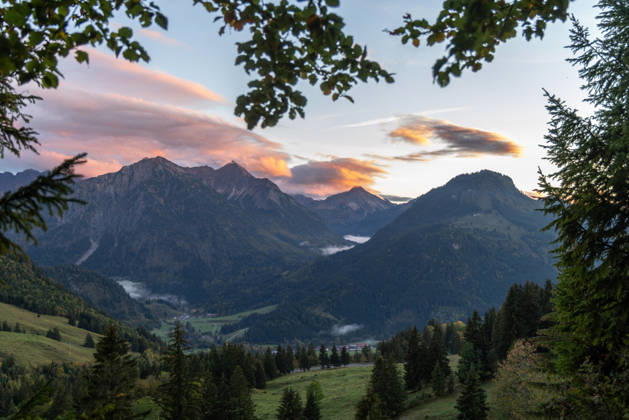 Herbstabend im Allgäu Die Wolken am Himmel leuchten im Licht der Abendsonne über den Gipfeln der Allgäuer Alpen., Bad Hindelang Bayern Deutschland
