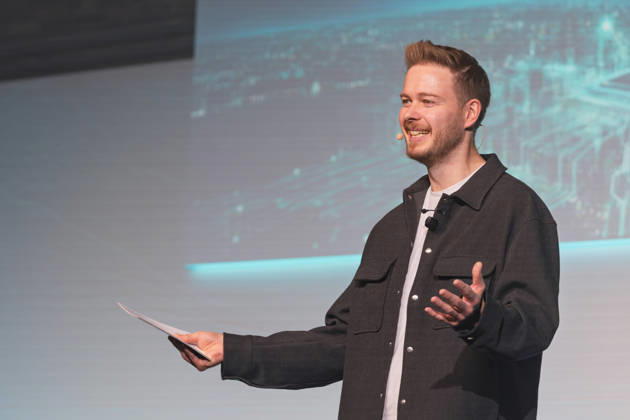 Berlin, 16.10.2026: Moderator Sascha Müller begrüßt mit Moderationskarten in der Hand und Headset-Mikrofon gut gelaunt das Publikum auf der Bühne der NeulandPro Connect 2026. Die zweitägige KI-Konferenz NeulandPro Connect 2026 findet am 16. und 17. Oktober im Westhafen Event & Convention Center (WECC) in Moabit statt, einem historischen Speichergebäude am Berliner Westhafen. Mit mehr als 50 Speakern sowie über 30 Workshops, Masterclasses und einem Hackathon richtet sich die Veranstaltung an Gründer, Führungskräfte, Unternehmen und KI-Interessierte. NeulandPro Connect 2026 - KI-Konferenz in Berlin