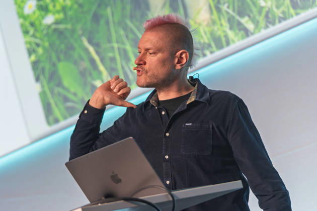 Berlin, 16.10.2026: Auf der NeulandPro Connect 2026 zeigt der Publizist und Digital-Vordenker Sascha Lobo während seines Vortrags mit dem Daumen auf sich selbst. Die zweitägige KI-Konferenz NeulandPro Connect 2026 findet am 16. und 17. Oktober im Westhafen Event & Convention Center (WECC) in Moabit statt, einem historischen Speichergebäude am Berliner Westhafen. Veranstalter ist NeulandPro, eine Bildungs- und Medienmarke rund um Künstliche Intelligenz. Mit Vorträgen, Workshops und Hackathons richtet sich die Konferenz vor allem an kleine und mittelständische Unternehmen, Gründer und Führungskräfte, die KI praktisch einsetzen wollen; erwartet werden bis zu 1.000 Gäste. NeulandPro Connect 2026 - KI-Konferenz in Berlin