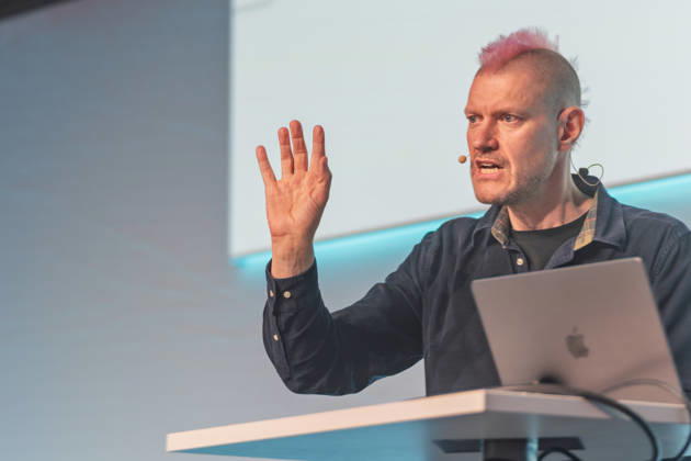 Berlin, 16.10.2026: Auf der NeulandPro Connect 2026 hebt der Publizist und Digital-Vordenker Sascha Lobo während seines Vortrags die Hand. Die zweitägige KI-Konferenz NeulandPro Connect 2026 findet am 16. und 17. Oktober im Westhafen Event & Convention Center (WECC) in Moabit statt, einem historischen Speichergebäude am Berliner Westhafen. Veranstalter ist NeulandPro, eine Bildungs- und Medienmarke rund um Künstliche Intelligenz. Mit Vorträgen, Workshops und Hackathons richtet sich die Konferenz vor allem an kleine und mittelständische Unternehmen, Gründer und Führungskräfte, die KI praktisch einsetzen wollen; erwartet werden bis zu 1.000 Gäste. NeulandPro Connect 2026 - KI-Konferenz in Berlin