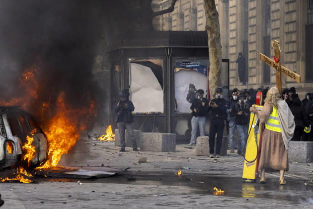 October 17, 2026, Paris, Å½Le-De-France, France: A man dressed as Jesus, wearing a yellow vest and carrying a wooden cross, stands near a burning car during demonstrations in Paris, France, on October 17, 2026. Students and Yellow Vest protesters demonstrated over rising living costs and conditions in education. Paris France  - ZUMAl165 20261017_zip_l165_022 Copyright: xOrinxLouisx