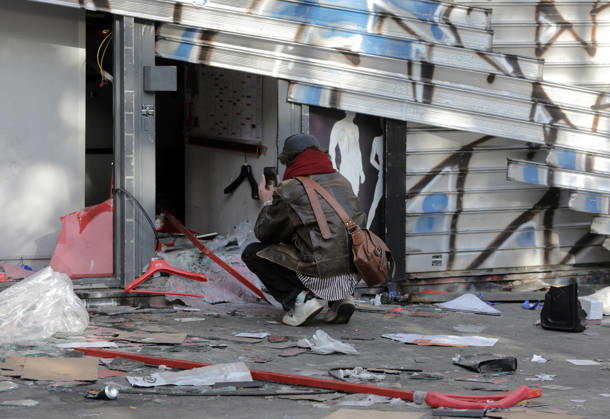 A man takes pictures of a vandalised shop near Republique Square in Paris, on Sunday, October 18, 2026. Residents awoke to scenes of widespread damage with shopfronts shattered, burnt out cars, charred bikes, and piles of glass and debris on the pavements of the French capital a day after riots erupted during protests against rising fuel prices, the cost of living and deteriorating public services, including schools.  PAR20261018111 MAYAxVIDON-WHITE