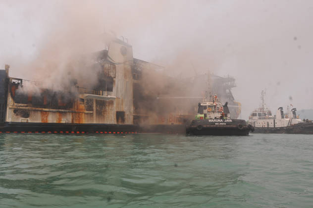 Efforts are underway to extinguish a fire that broke out on a passenger ferry in Indonesia s Cilegon PELABUHAN MERAK, CILEGON, INDONESIA - OCTOBER 21: Fireboats take turns spraying water onto the passenger ferry KMP Batumandi to cool down the vessel after it caught fire while preparing to dock off Merak Port in Cilegon, Banten, Indonesia on Wednesday, October 21, 2026. The vessel caught fire on Tuesday, October 20, and rescue operations remain underway as the ship continues to emit smoke. Water is continuously sprayed to cool the vehicle deck containing numerous cars, motorcycles, buses, and trucks, while authorities confirm no fatalities have been reported. Dasril Roszandi Anadolu Pelabuhan Merak Indonesia. Editorial use only. Please get Copyright: x2026xAnadoluxDasrilxRoszandix