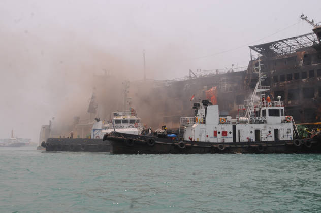 Efforts are underway to extinguish a fire that broke out on a passenger ferry in Indonesia s Cilegon PELABUHAN MERAK, CILEGON, INDONESIA - OCTOBER 21: Fireboats take turns spraying water onto the passenger ferry KMP Batumandi to cool down the vessel after it caught fire while preparing to dock off Merak Port in Cilegon, Banten, Indonesia on Wednesday, October 21, 2026. The vessel caught fire on Tuesday, October 20, and rescue operations remain underway as the ship continues to emit smoke. Water is continuously sprayed to cool the vehicle deck containing numerous cars, motorcycles, buses, and trucks, while authorities confirm no fatalities have been reported. Dasril Roszandi Anadolu Pelabuhan Merak Indonesia. Editorial use only. Please get Copyright: x2026xAnadoluxDasrilxRoszandix