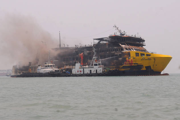 Efforts are underway to extinguish a fire that broke out on a passenger ferry in Indonesia s Cilegon PELABUHAN MERAK, CILEGON, INDONESIA - OCTOBER 21: Fireboats take turns spraying water onto the passenger ferry KMP Batumandi to cool down the vessel after it caught fire while preparing to dock off Merak Port in Cilegon, Banten, Indonesia on Wednesday, October 21, 2026. The vessel caught fire on Tuesday, October 20, and rescue operations remain underway as the ship continues to emit smoke. Water is continuously sprayed to cool the vehicle deck containing numerous cars, motorcycles, buses, and trucks, while authorities confirm no fatalities have been reported. Dasril Roszandi Anadolu Pelabuhan Merak Indonesia. Editorial use only. Please get Copyright: x2026xAnadoluxDasrilxRoszandix