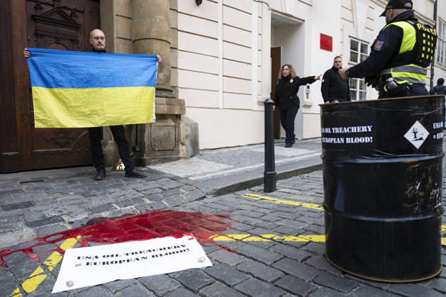 News Bilder des Tages Activists from the Kaputin group poured artificial blood (an easily washable food coloring) from an oil drum during a brief visual performance in front of the U.S. Embassy in Prague on October 21, 2026. There is a poster on the ground that reads: USA OIL TREACHERY = EUROPEAN BLOOD! (CTKxPhoto MichalxKamaryt) CTKPhotoP2026102105260  CTKPhotoP2026102105260