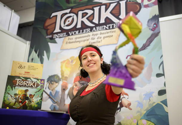 Sieger Bestes Kinderspiel Toriki: Eine Insel voller Abenteuer (Verlag: Mirakulus, Autor: Wojciech Grajkowski). Lea Taubmann vom Verlag Mirakulus zeigt den Preis, am 21.10.2026 Messe SPIEL Essen vom 22.10 - 25.10.2026 in E s s e n Deutschland. Grugahalle
