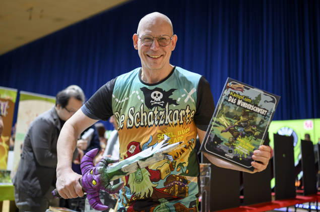 Ein Mitarbeiter präsentiert das Spiel - Kampf um das Wunderschwert - von Peasoup (Dänemark), 3-in-1 Spiel, Gamebook, Brettspiel und interaktive App in einem, Neuheitenschau, am 21.10.2026 Messe SPIEL Essen vom 22.10 - 25.10.2026 in E s s e n Deutschland. Grugahalle
