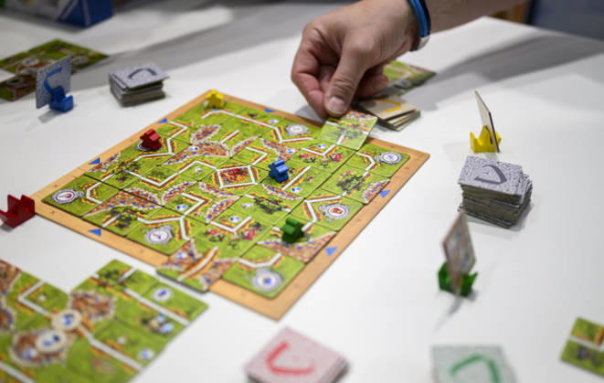 Feature, das Spiel Carcassonne Labyrinth aus der Verlagskooperation Ravensburger und Hans im Glück, eine Hand legt ein Plättchen, Neuheitenschau, am 21.10.2026 Messe SPIEL Essen vom 22.10 - 25.10.2026 in E s s e n Deutschland. Grugahalle