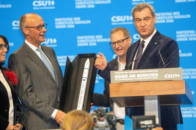 Markus Söder, CSU-Vorsitzender, Bayerischer Ministerpräsident, Martin Huber, CSU-Generalsekretär, schenken Bundeskanzler Friedrich Merz ein Modell der Rakete des bayerischen Unternehmens Isar Aerospace, CSU-Parteitag, Messe München, 24. Oktober 2026 Deutschland, München, 24. Oktober 2026, Markus Söder, CSU-Vorsitzender, Bayerischer Ministerpräsident, und Martin Huber, CSU-Generalsekretär, schenken Bundeskanzler Friedrich Merz ein Modell der Rakete des bayerischen Unternehmens Isar Aerospace, nach Ende seiner Rede beim CSU-Parteitag am 23. und 24. Oktober 2026 in der Messe München, Politiker, Bayern