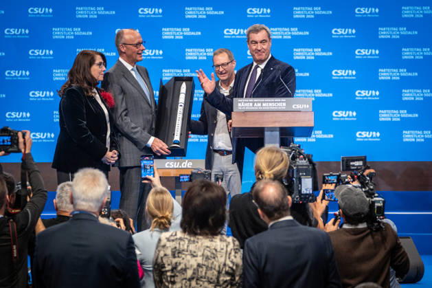 Bundeskanzler Friedrich Merz mit dem CSU-Parteivorsitzenden Markus Söder auf dem Parteitag, mit Tanja Schorer-Dremel und Martin Huber bei der Übergabe einer Rakete als Modell an den Bundeskanzler;Parteitag der CSU in München, München Bayern Deutschland Messegelände München