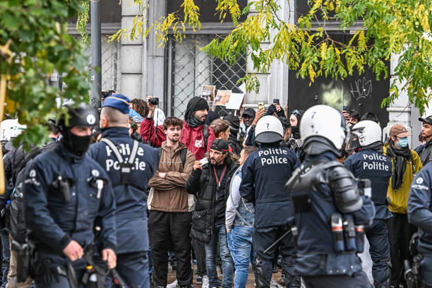 Riot police officers in protective gear surround a group of demonstrators, some wearing face coverings and others unmasked, during student protests in central Brussels, Belgium, on 24 October 2026. Several people film the police operation with their mobile phones as officers confront the protesters amid unrest in the city centre.