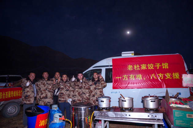 (261025) -- BAQEN, Oct. 25, 2026 -- Du Guoping (1st R) poses for a photo with his staff members at a temporary shelter in Maru Township of Baqen County, Nagqu City, southwest China s Xizang Autonomous Region, Oct. 24, 2026. After a 7.0-magnitude earthquake struck Baqen County in Nagqu, southwest China s Xizang Autonomous Region, on Thursday, Du Guoping, owner of a dumpling restaurant in Xigaze, postponed the opening of his two new restaurants and headed to the disaster zone with his staff. It took only about 10 minutes to make the decision that we would go to Baqen and cook dumplings for earthquake-affected residents, Du said. The team loaded more than 1,500 kilograms of dumplings onto vehicles and set off from Xigaze at midnight on