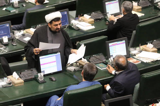 October 25, 2026, Tehran, Iran: A white-turbaned cleric stands at his desk reading a sheet of paper as two seated lawmakers look toward him at the Islamic Consultative Assembly in Tehran, Iran, on October 25, 2026. Speaker Mohammad Bagher Ghalibaf chaired the October 25 session, which combined physical attendance at the Islamic Consultative Assembly with participation by video link. Tehran Iran - ZUMAi98_ 20261025_zih_i98_118 Copyright: xIcanax